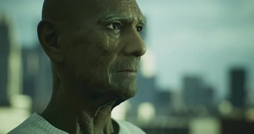 Un anciano mira pensativo el horizonte de la ciudad durante la tarde