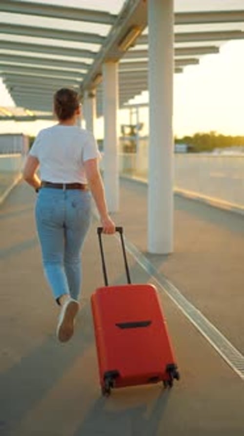 Mulher caucasiana puxando uma mala e chegando atrasada para o voo. Câmera lenta