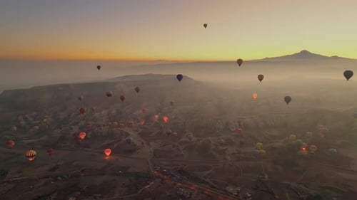 Drone view of hundreds of colorful hot air balloons soaring at sunrise in Cappadocia