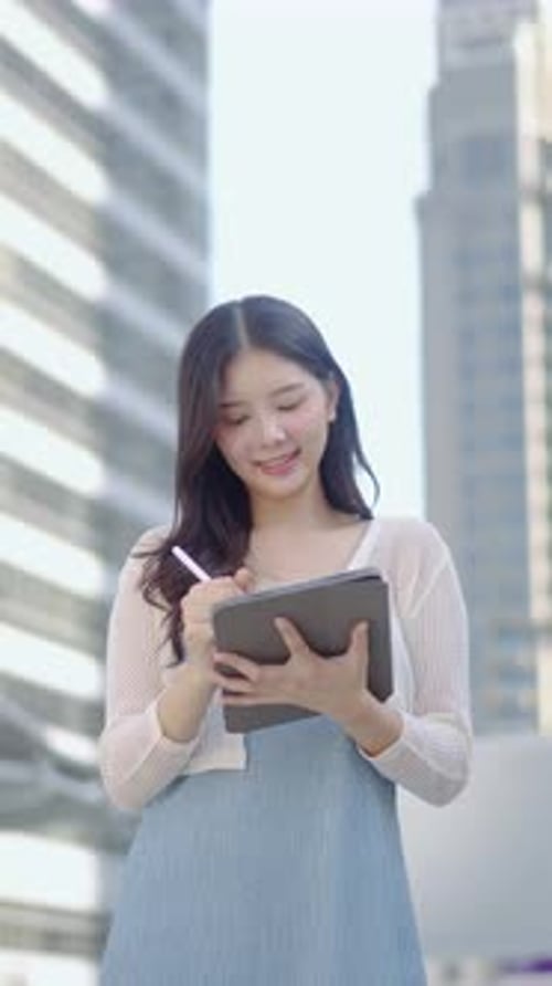 Woman Writes on Tablet in Urban Setting