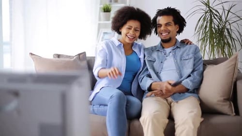 Smiling Couple Relaxing on Sofa Watching Television
