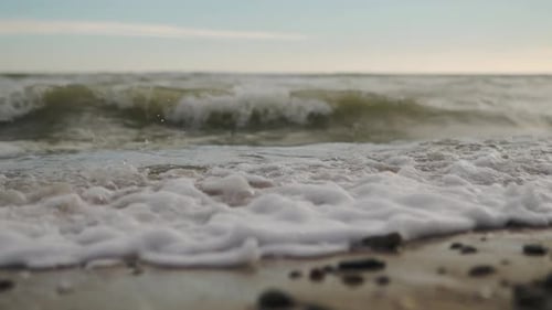 Zeitlupe der Meereswellen, die den nördlichen Sandstrand mit Wasser und Schaum überschwemmen, die Kamera bewegt sich stürmisch entlang