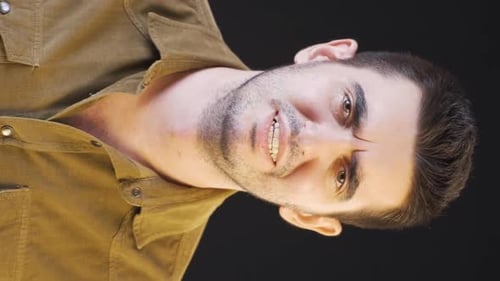 Young Man Touching Face Against Black Background