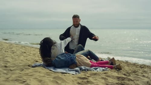 Family tickle fight on beautiful beach holiday vacation with mom dad and child