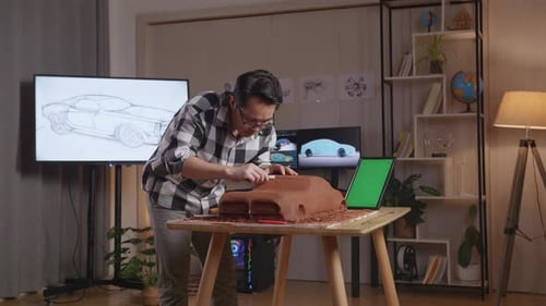 Asian Man Automotive Designer With Green Screen Tablet Using Rake Or Wire To Smooth Out The Surface