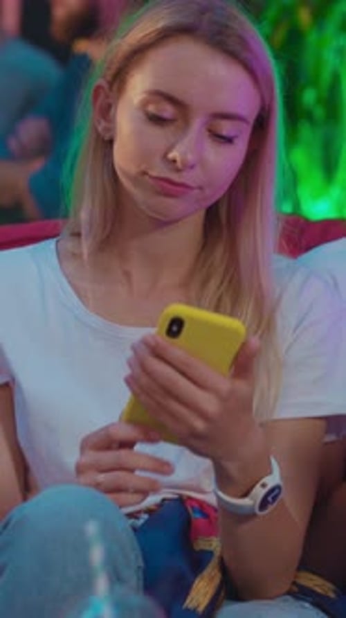 Blonde Woman Using Smartphone in Urban Nightlife Scene