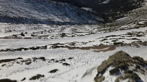 Push forward tilt up reveal aerial shot over an endless snow covered wild mountain range.