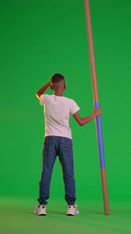 A Schoolboy Stares Into the Distance Holding a Blue Stick at the Green Screen