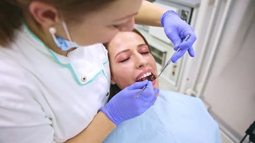 Young woman having teeth examined by female dentist in dental clinic.