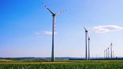 Powerful wind turbines rotate in the wind. Low angle view at the wind mills in the fields.