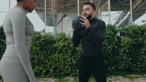 Trainingseinheit im Freien, schwarze Frau und männlicher Trainer mit Medizinball