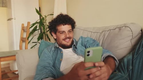 Man Relaxing on Sofa Using Smartphone