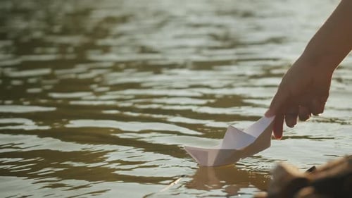 Woman Hand Puts Paper Ship Boat on Water in the Park Close Up Origami Paper Crane on a Pond Natural
