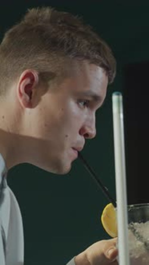 Close Up Side Shot of Gentleman in White Shirt Holding Cue Stick and Sipping Lemon Drink
