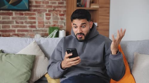 Excited Man Reacts to Content on His Mobile Phone