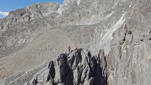 Mountain Climber Scaling Precarious Ridge Navigating Rugged Himalayan Terrain with Snow Capped Mount