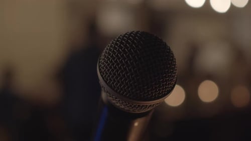 Circular view of a professional microphone on an evening stage in a building with blurred background