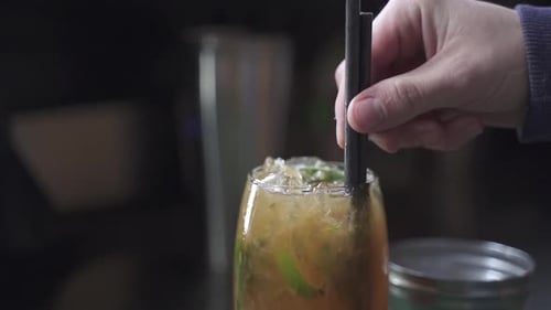 Zeitlupenaufnahme einer Person, die Strohhalm in Tasty Cynar Drink steckt, Nahaufnahme