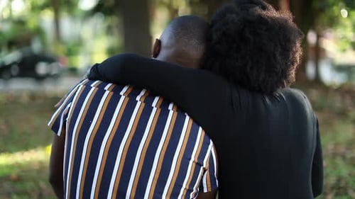 Woman putting arm around man at park