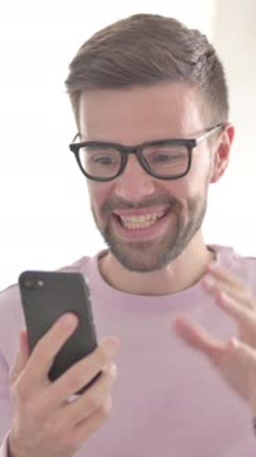 Excited Man Reacts to News on Smartphone