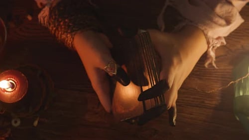 Woman Shuffles Tarot Cards in Dim Candlelight