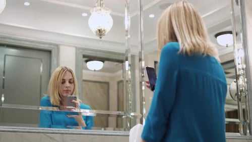 Woman Using Smartphone in Bathroom Mirror Reflection