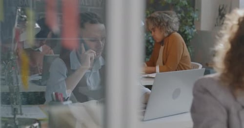 Young Man Office Employee Speaking on Mobile Phone Consulting Client Checking Documents and Using