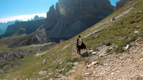 Girl hiking an amazing viewing path in dolomites mountains; following shot
