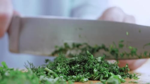 a Woman's Hand Cuts Green Onions with a Knife on a Wooden Chopping Board Slicing Greens for Salad