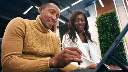 Black male and female workers in an office discussing business using a tablet. Slow motion