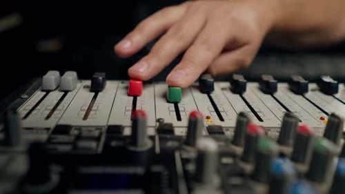 close-up shot of the male hand of a sound engineer switching settings on mixing console recording