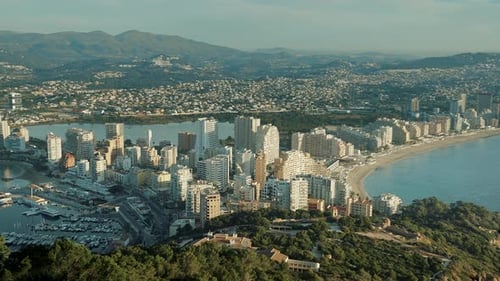 Modern coastal city with tall buildings on a sunny day next to the sea.