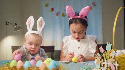 Children Decorate Easter Eggs Sitting at the Table in the Living Room