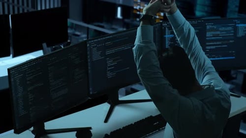 Side View Of Tired Asian Man Stretching While Write Code With Multiple Computer Screens In office