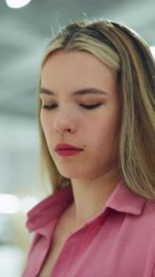 Dame en chemise rose observant un haut noir dans un centre commercial lumineux