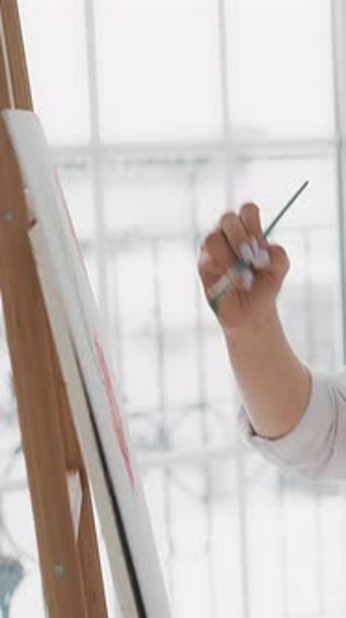 Woman Draws Ornament on Canvas Sitting in Light Art Studio