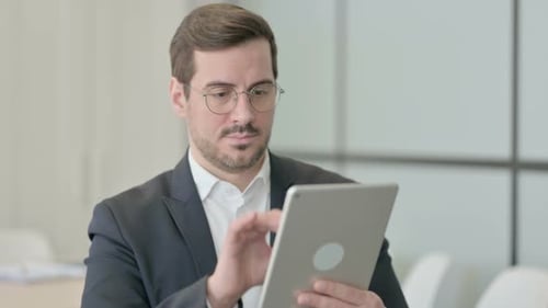 Young Adult Uses Tablet in Bright Office