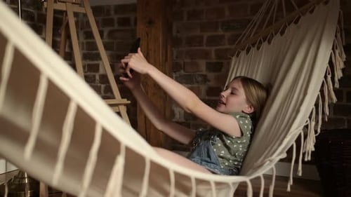 Girl Relaxing in Hammock Using Smartphone