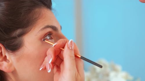 Artist Applying Makeup Eyeshadow on Woman's Eyelid in Studio