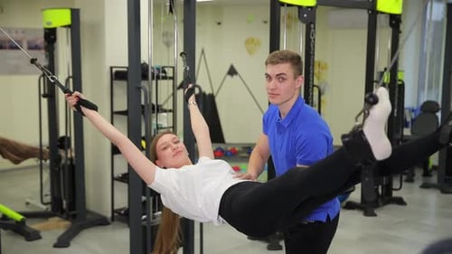A Man Helps a Woman in the Gym Emphasizing Teamwork and Support