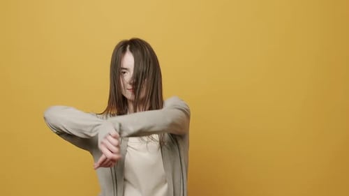 Young Woman Dances Energetically on Yellow Background