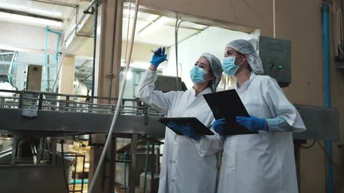 Deux superviseurs féminins inspectent le processus de production sur le convoyeur d'une usine alimentaire.