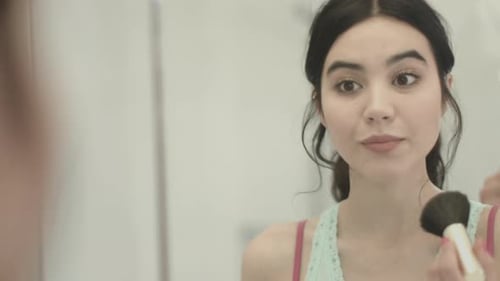 Pretty Young Asian female applying make up in bathroom