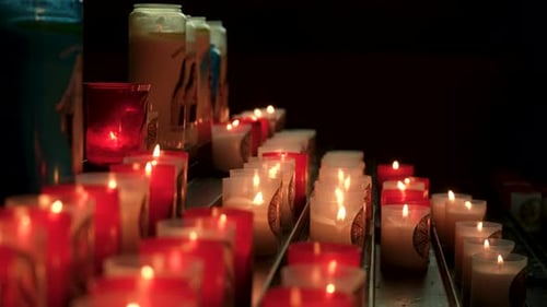 Closeup Tracking Shot of Glowing Candles in Church or Temple with Dark Interior Creating a Peaceful