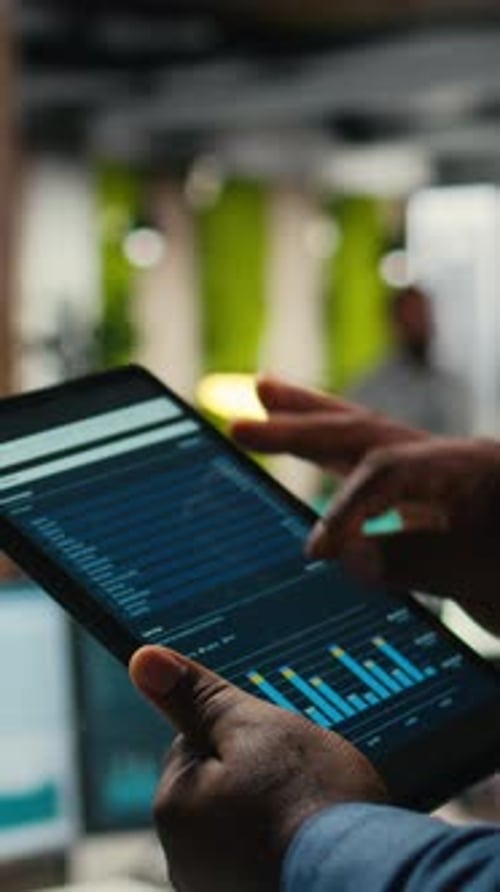 Vertical Video Close Up of Black Employee Engages in Charts Analysis Session on Tablet