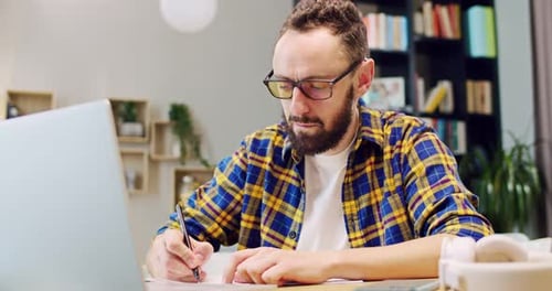 Man Works From Home with Laptop and Smartphone