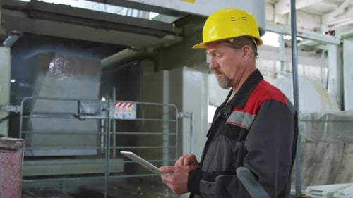 Technician Operating Machine with Digital Tablet at Stone Factory