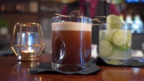 Two beverages on bar margarita and chocolate coffee cocktail with bartender in background, slider cl
