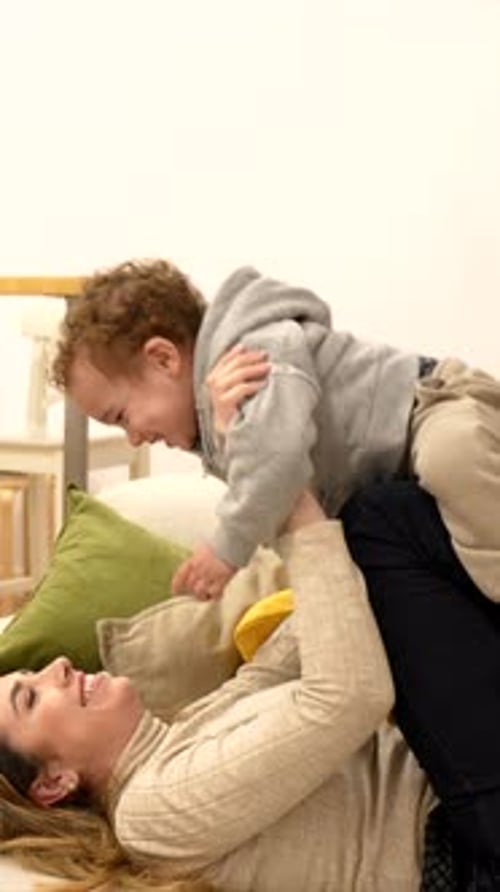 Woman Lying on Couch Holding Baby in Air