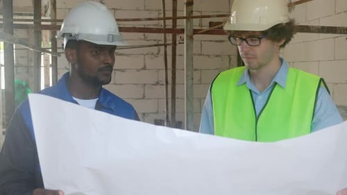 Construction Workers Reviewing Blueprint on a Building Site